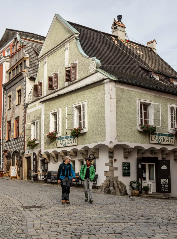 Charming cobblestone street in Český Krumlov, Czech Republic, with colorful historic houses and cozy cafés — a highlight on IzzyTrip’s Central Europe tours.