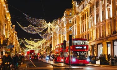 London’s Oxford Street glowing with Christmas lights and red double-decker buses — festive atmosphere on IzzyTrip’s London city tours.