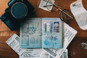 open passport, camera, itinaries on a table layed out