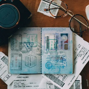 open passport, camera, itinaries on a table layed out